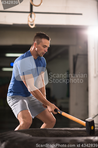 Image of man workout with hammer and tractor tire