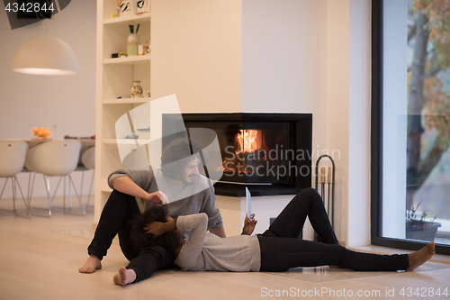 Image of multiethnic couple using tablet computer on the floor