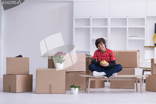 Image of boy sitting on the table with cardboard boxes around him