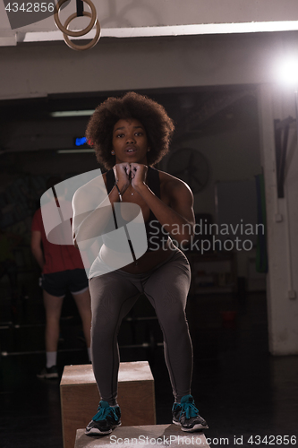 Image of black female athlete is performing box jumps at gym