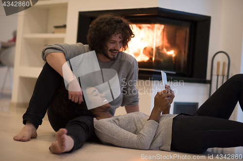 Image of multiethnic couple using tablet computer on the floor