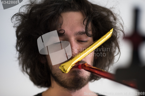 Image of Portrait of a man in party hat blowing in whistle