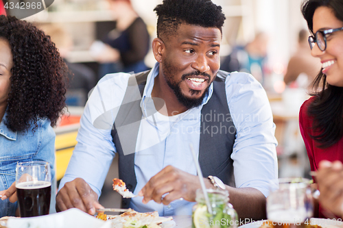 Image of happy friends eating at restaurant