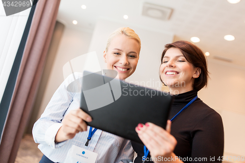 Image of businesswomen with tablet pc and conference badges