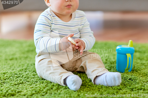 Image of baby boy on floor and eating rice cracker at home