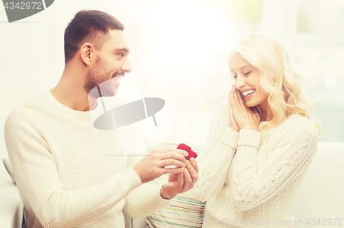 Image of man giving woman engagement ring for christmas