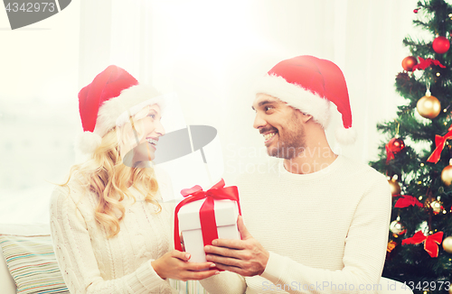 Image of happy couple at home with christmas gift box