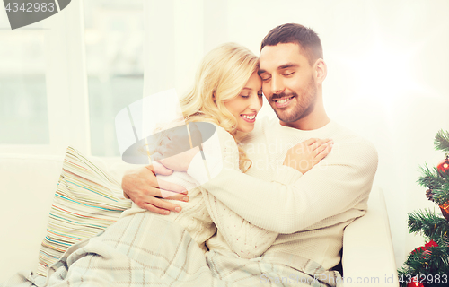 Image of happy couple hugging on sofa at home