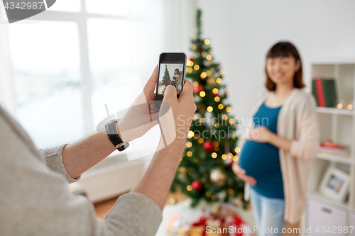 Image of husband photographing pregnant fife at christmas