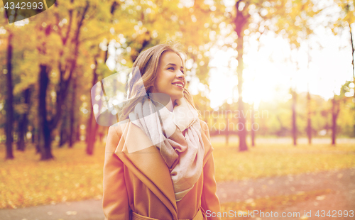 Image of beautiful happy young woman walking in autumn park