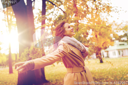 Image of beautiful happy young woman walking in autumn park