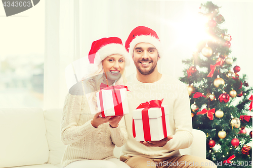 Image of happy couple at home with christmas gift boxes