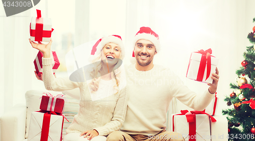 Image of happy couple at home with christmas gift boxes