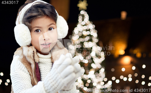 Image of happy girl wearing earmuffs over christmas lights