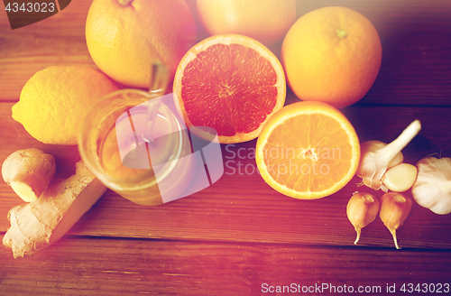 Image of honey, citrus fruits, ginger and garlic on wood