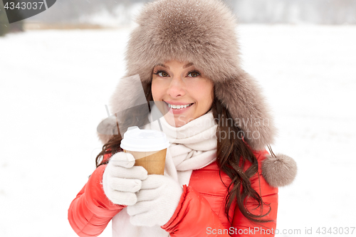 Image of happy woman in winter fur hat with coffee outdoors