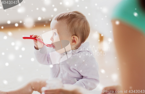 Image of mother and baby with spoon eating at home