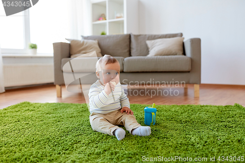 Image of baby boy on floor and eating rice cracker at home