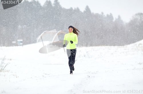 Image of happy smiling woman running outdoors in winter