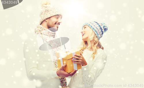 Image of smiling couple in winter clothes with gift box