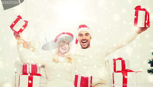 Image of happy couple at home with christmas gift boxes