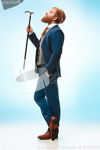 Image of The barded man in a suit holding cane.