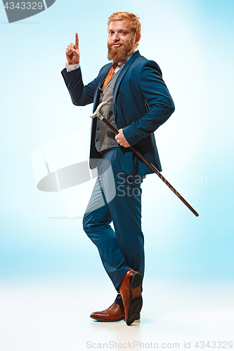 Image of The barded man in a suit holding cane.