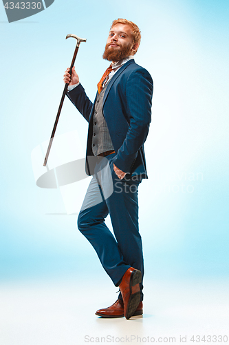 Image of The barded man in a suit holding cane.