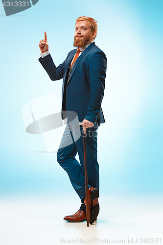 Image of The barded man in a suit holding cane.