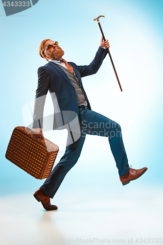 Image of The barded man in a suit holding cane.