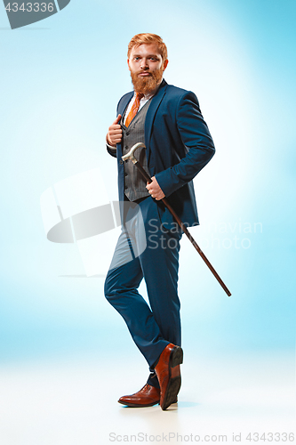 Image of The barded man in a suit holding cane.