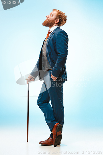 Image of The barded man in a suit holding cane.