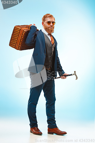 Image of The barded man in a suit holding cane.