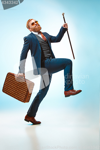 Image of The barded man in a suit holding cane.