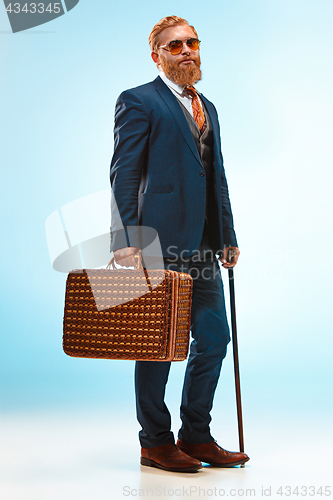 Image of The barded man in a suit holding cane.