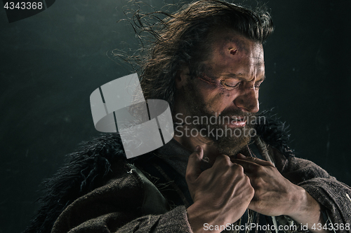 Image of Portrait of a brutal bald-headed viking in a battle mail posing against a black background.