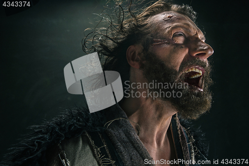 Image of Portrait of a brutal bald-headed viking in a battle mail posing against a black background.