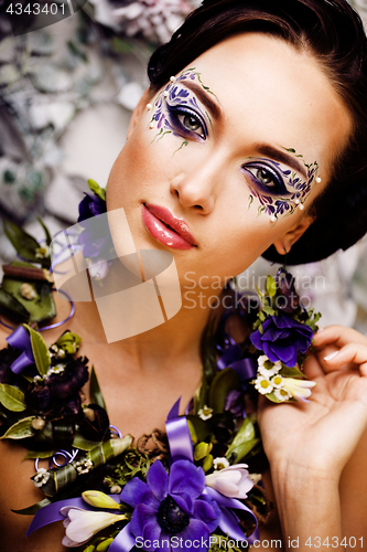 Image of floral face art with anemone in jewelry, sensual young brunette 