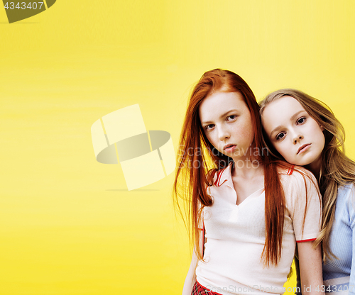 Image of lifestyle people concept: two pretty stylish modern hipster teen girl having fun together, happy smiling making selfie close up on yellow background, diverse type girls
