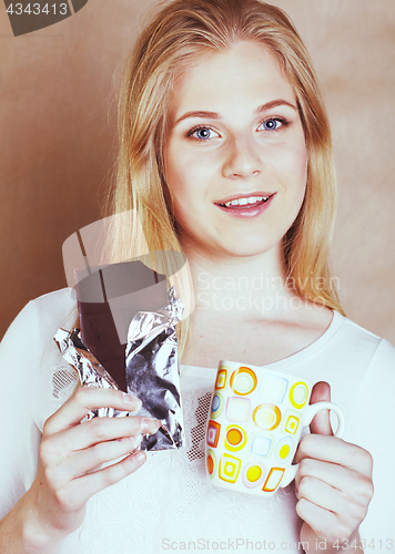 Image of young cute blond girl eating chocolate and drinking coffee close