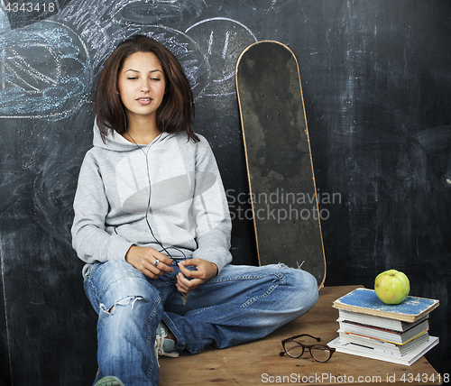 Image of young cute teenage girl in classroom at blackboard seating on table smiling, modern pupil hipster concept, lifestyle people