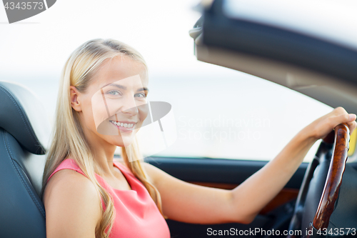 Image of happy young woman driving convertible car