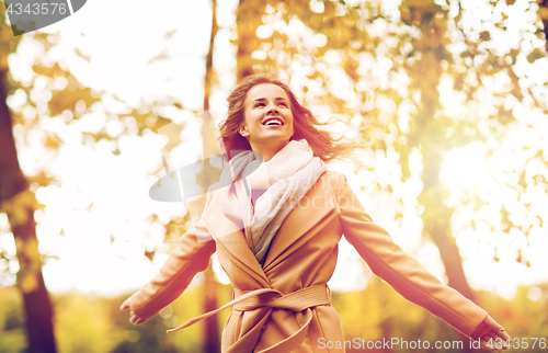 Image of beautiful happy young woman walking in autumn park