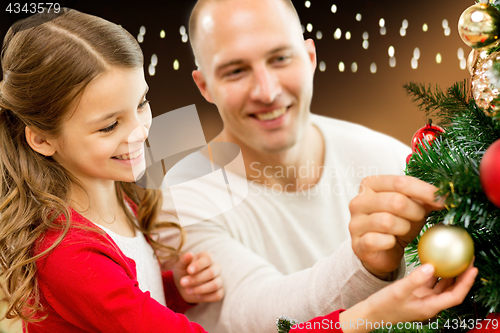 Image of happy family decorating christmas tree at home