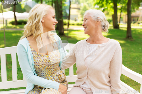 Image of daughter with senior mother hugging on park bench