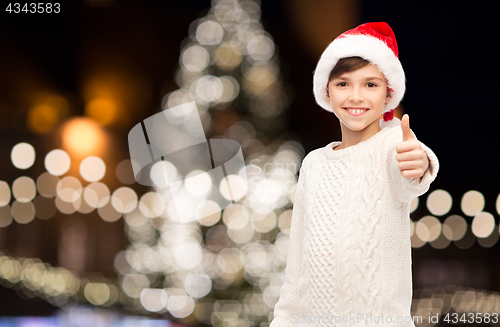 Image of boy in santa hat showing thumbs up at christmas