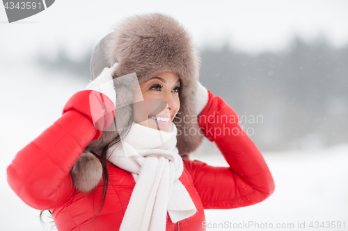 Image of happy smiling woman in winter fur hat outdoors