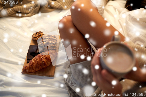 Image of close up of woman with sweets and cocoa in bed