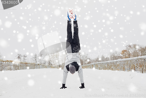 Image of young man doing handstand in winter