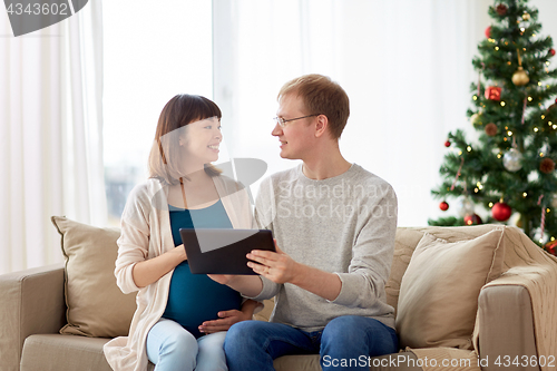 Image of man and pregnant wife with tablet pc at christmas